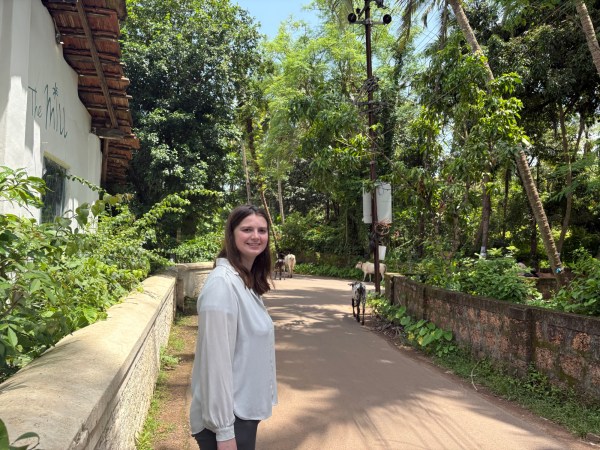 Emily walking along a leafy lane with goats in South Goa